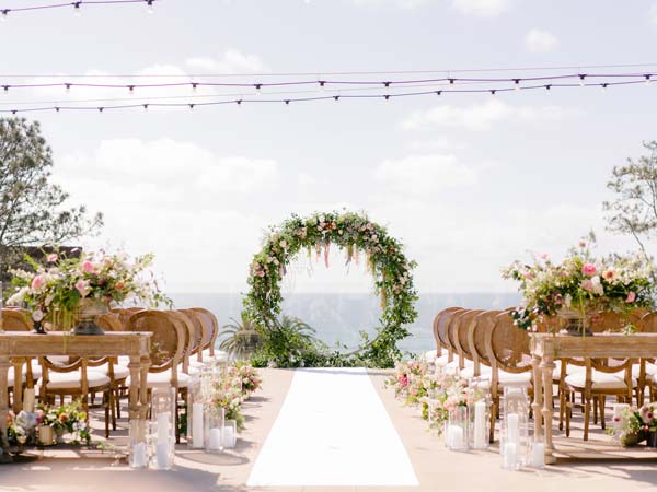 A wedding aisle with large wreath at the end of the aisle.