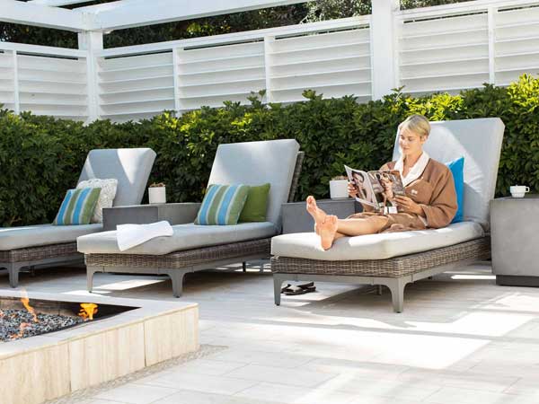 Woman reading on patio with fire pit at L'Auberge Del Mar